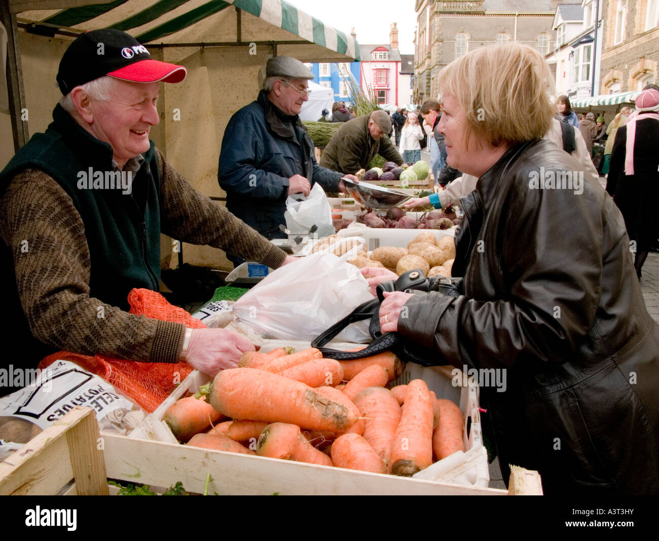 Donna in chat mentre acquistare fresca verdura invernale Natale street e il mercato degli agricoltori food fair Aberystwyth Ceredigion REGNO UNITO Foto Stock