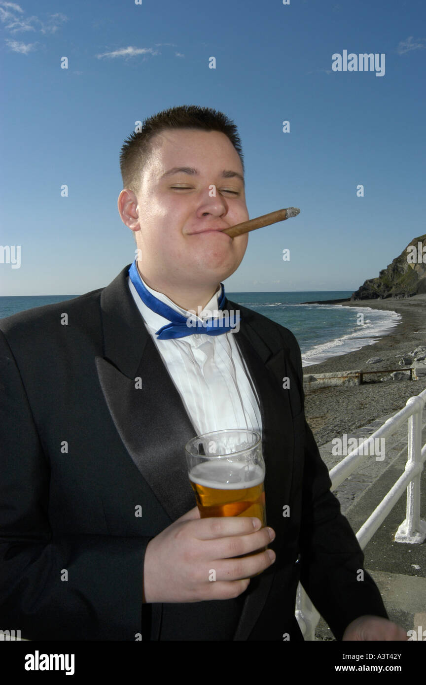 Studente maschio in giacca di fumare un buon sigaro e bere una pinta di birra Aberystwyth University può palla, sul lungomare Wales UK Foto Stock