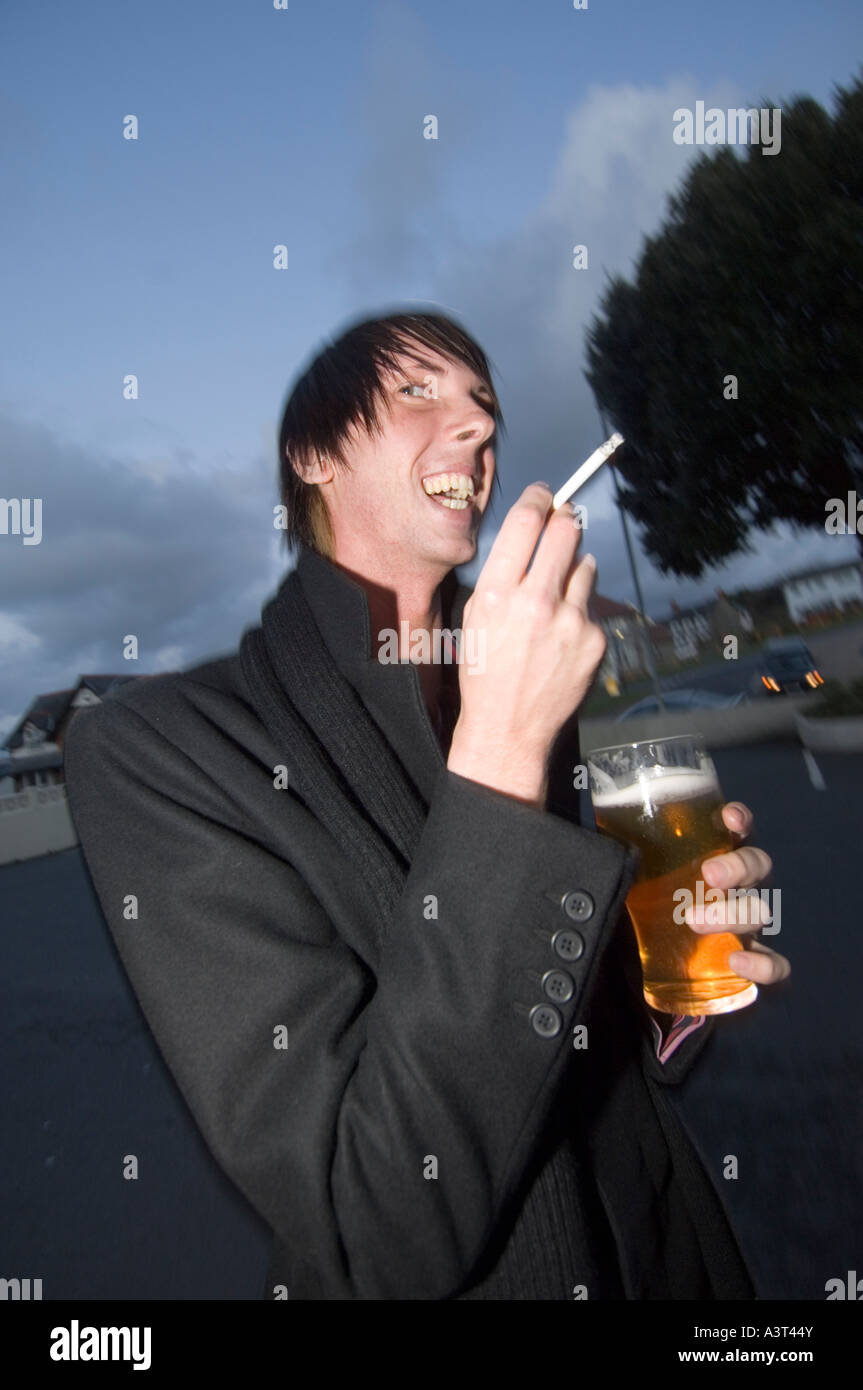Un uomo di fumare sigarette e bere apint di birra in esterno ad un matrimonio in Aberystwyth Ceredigion REGNO UNITO GALLES Foto Stock