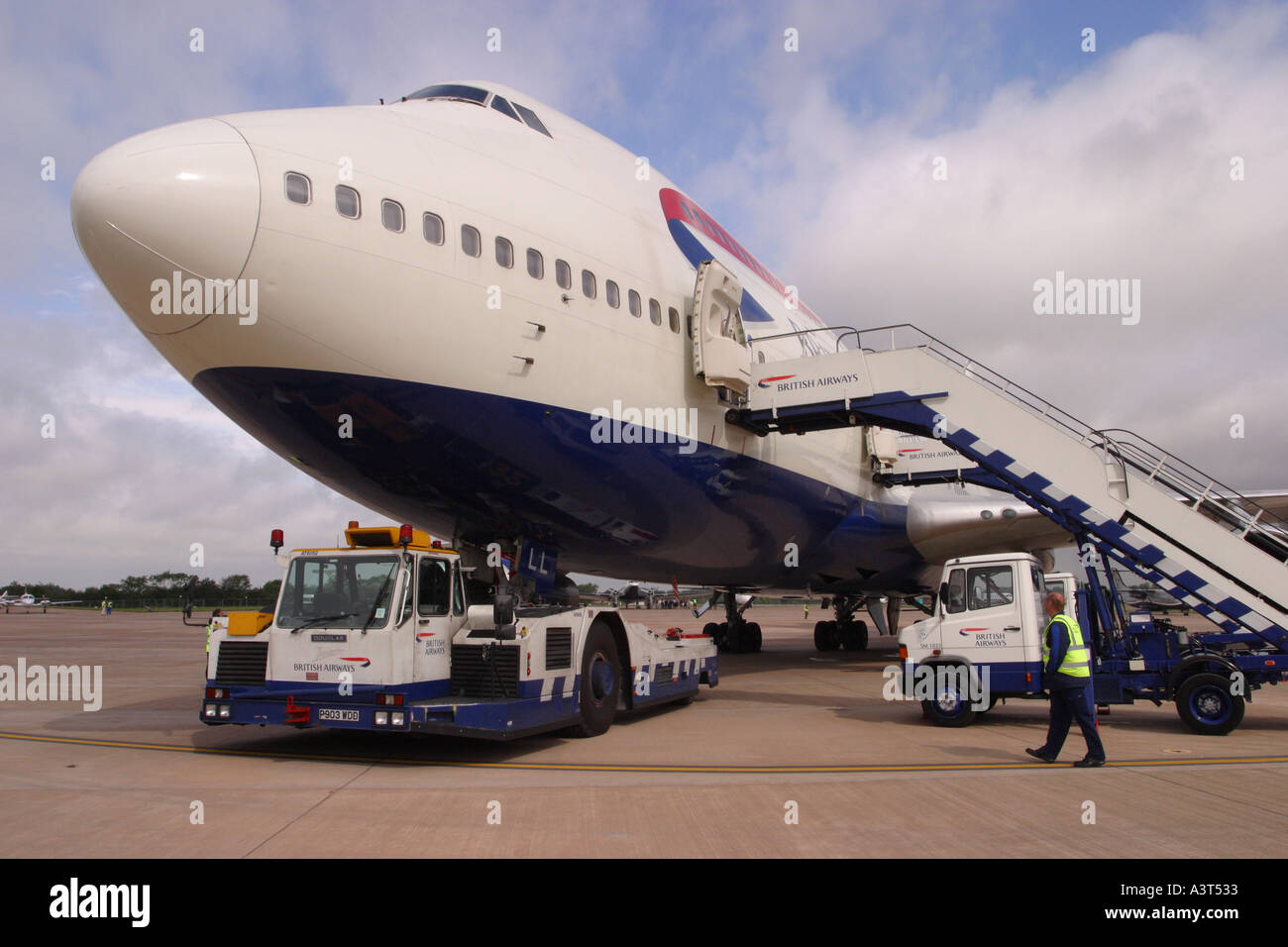 British Airways Boeing 747 jumbo parcheggiato su un aeroporto grembiule con rimorchiatore e aria scale Foto Stock