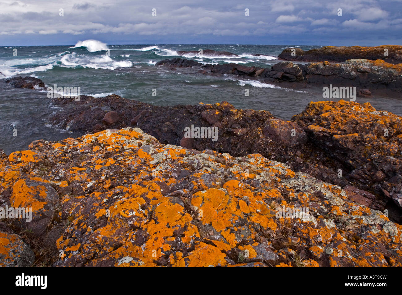 Licheni arancioni si aggrappano alla penisola Keweenaw litorale come grande Lago Superior crash onde vicino al porto di rame Foto Stock