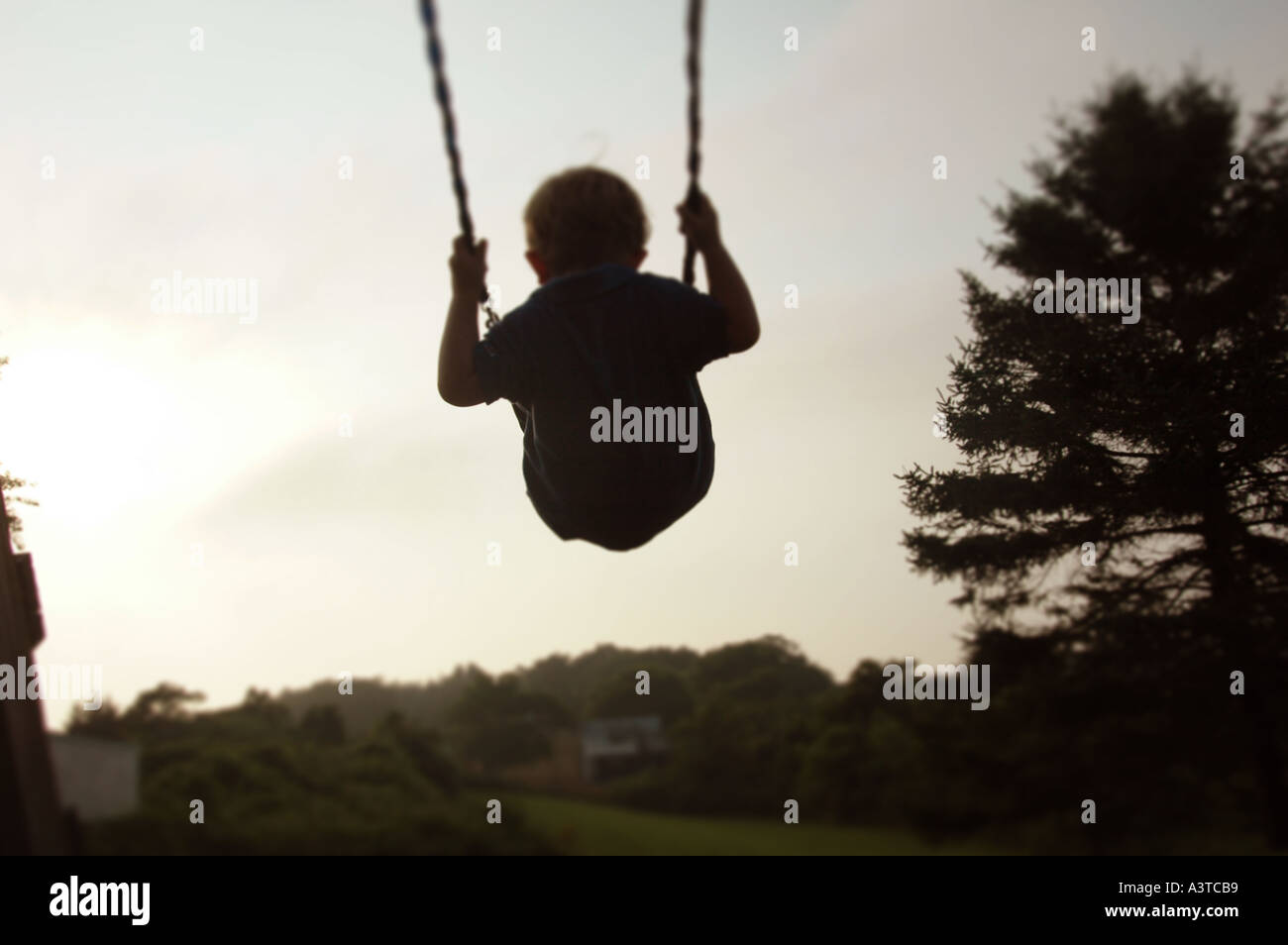 Bambini che giocano piccolo ragazzo basculante in swing Foto Stock