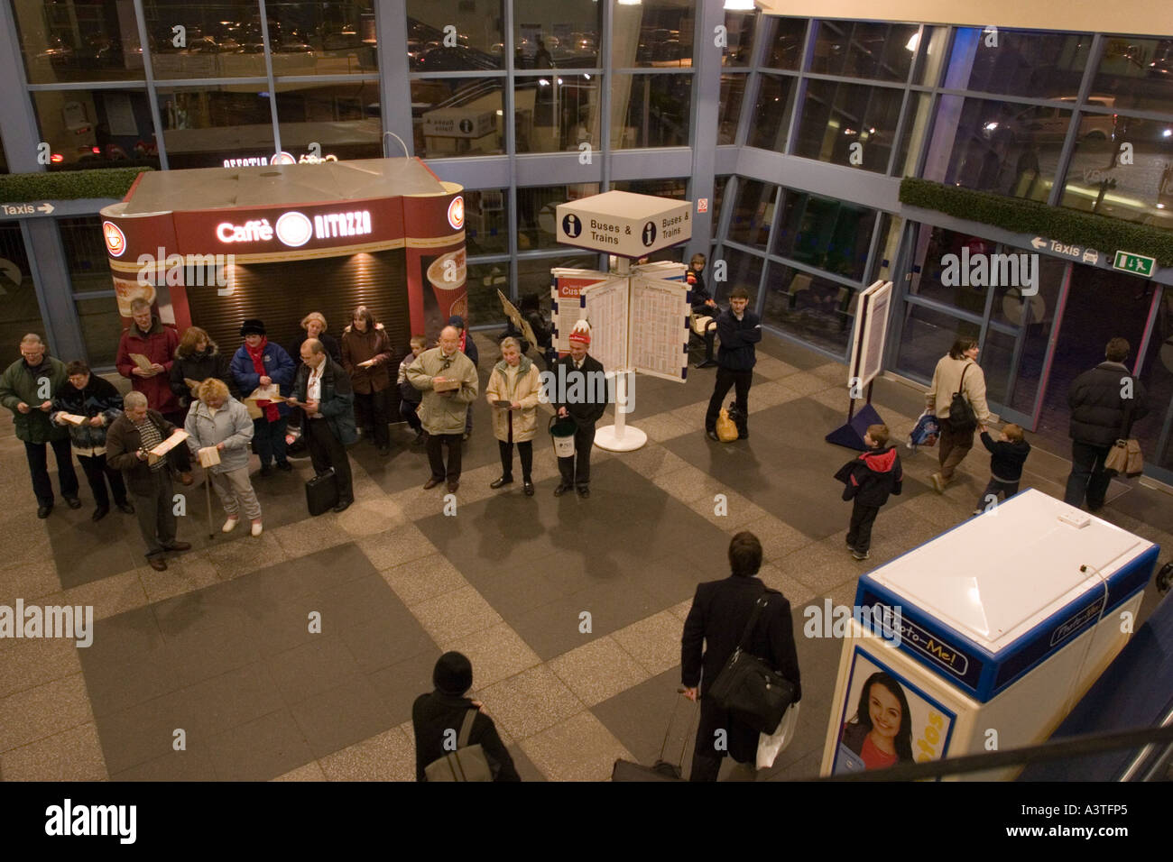 Banda di ottoni e carol cantanti nel foyer della stazione ferroviaria Foto Stock