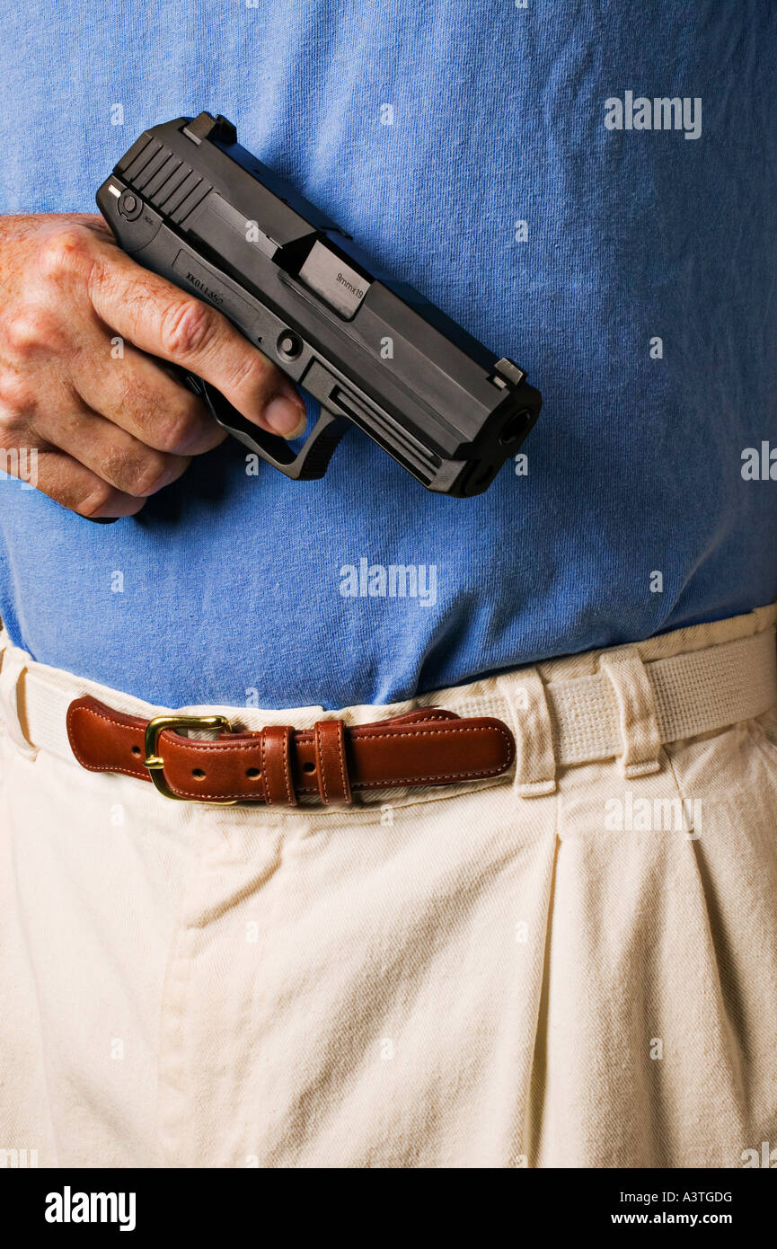 L'uomo con la maglietta blu pistola di contenimento 9mm gun Foto Stock