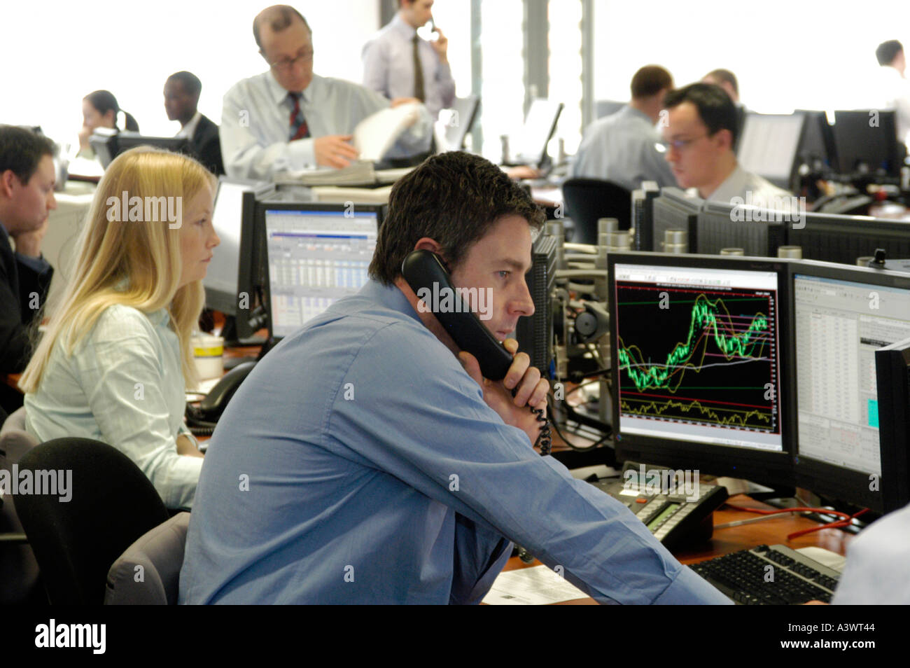 Cambio operatore guardando gli schermi dei computer di trading floor, City of London, England, Regno Unito Foto Stock