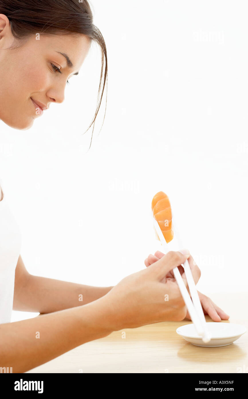Una giovane donna di mangiare sushi con bacchette Foto Stock