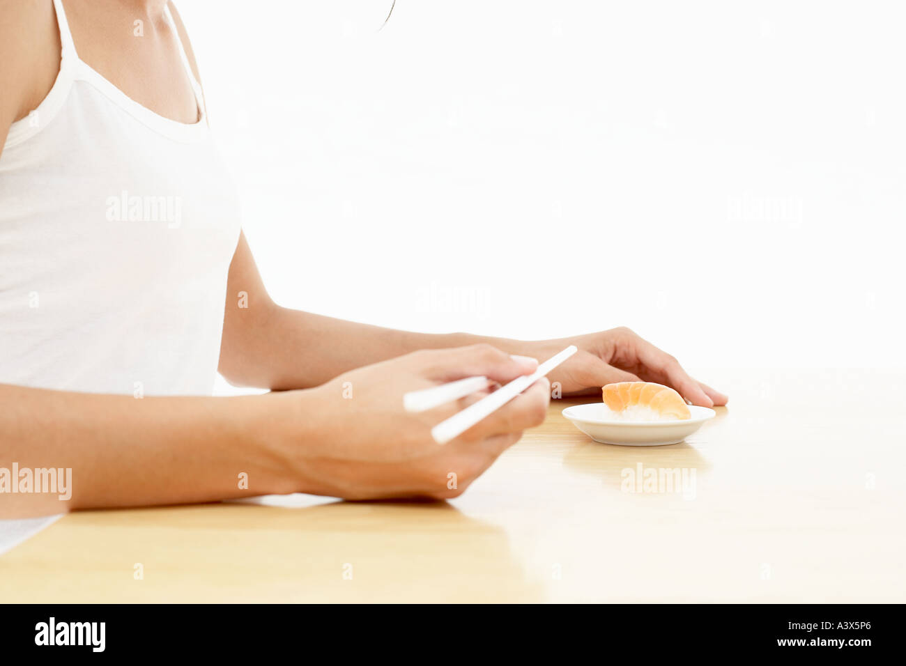 Una giovane donna di mangiare sushi con bacchette Foto Stock