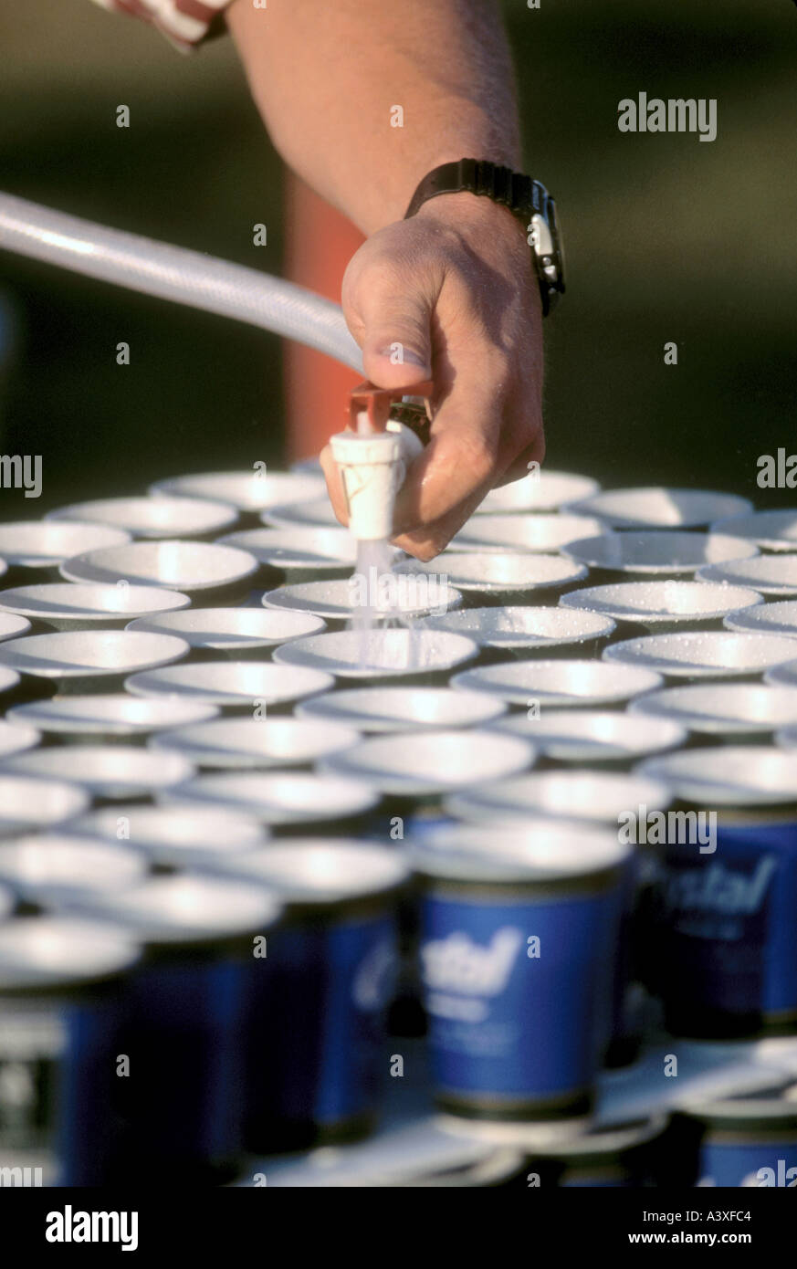 Riempire le coppe d'acqua per la gara di maratona a lunga distanza per i partecipanti caldi Foto Stock