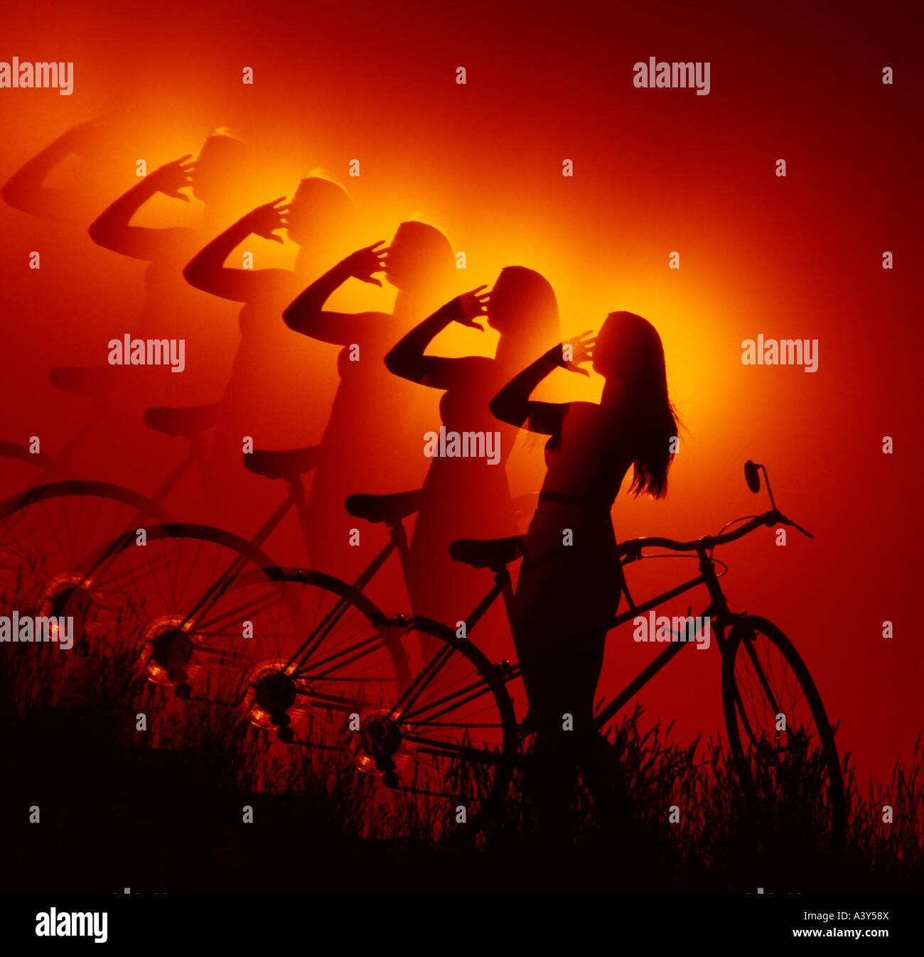 Ripetere la silhouette di donna giovane e bicicletta contro il sole di setting Foto Stock