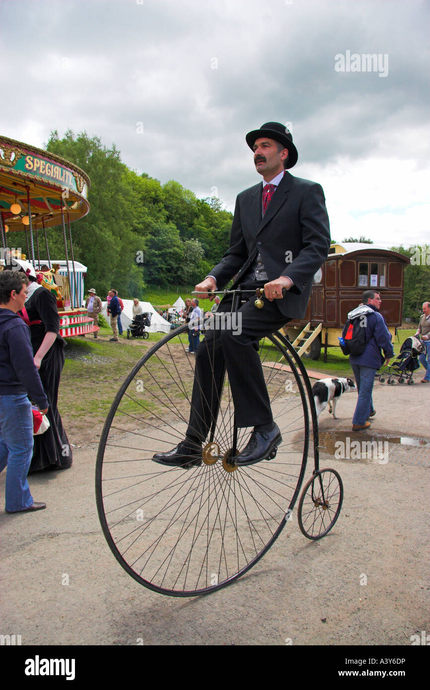 Uomo che cavalca Penny Farthing ciclo a Blists Hill cittadina in stile vittoriano, Museo di Ironbridge, Shropshire, Inghilterra Foto Stock