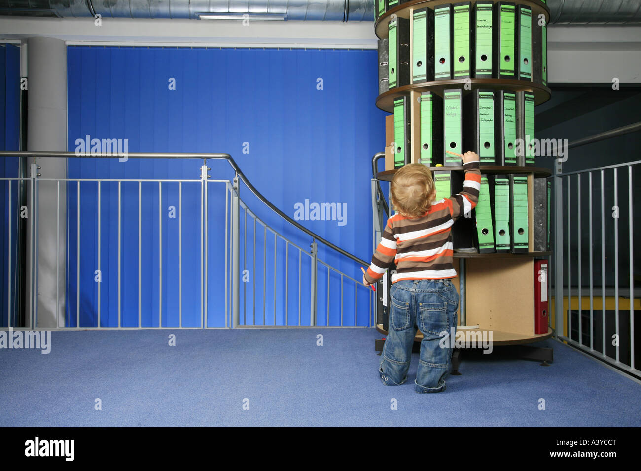 Piccolo Ragazzo davanti a una cartella rack di stoccaggio in ufficio Foto Stock