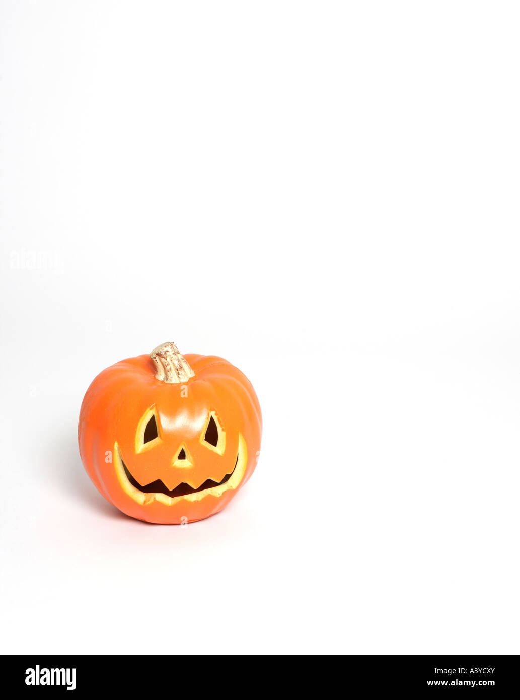 Un singolo in plastica arancione zucca con occhi naso e bocca posta contro un bianco paesaggio sfondo formato Foto Stock
