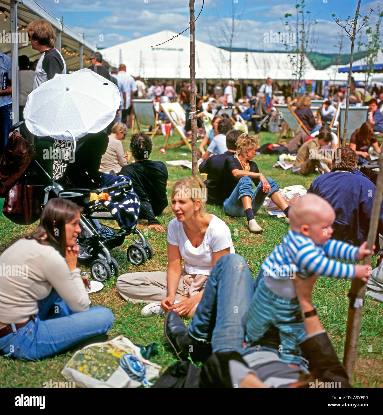 La folla di gente seduta nella luce del sole al di fuori in giardino presso il Festival di Fieno Hay-on-Wye, Wales, Regno Unito KATHY DEWITT Foto Stock