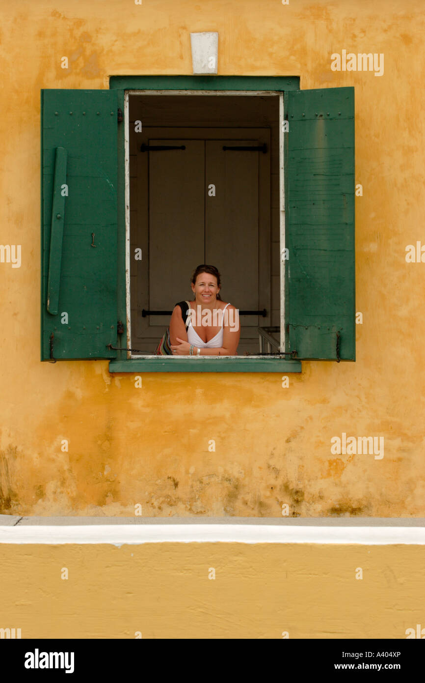 Donna appoggiata attraverso una finestra ceil. Foto Stock