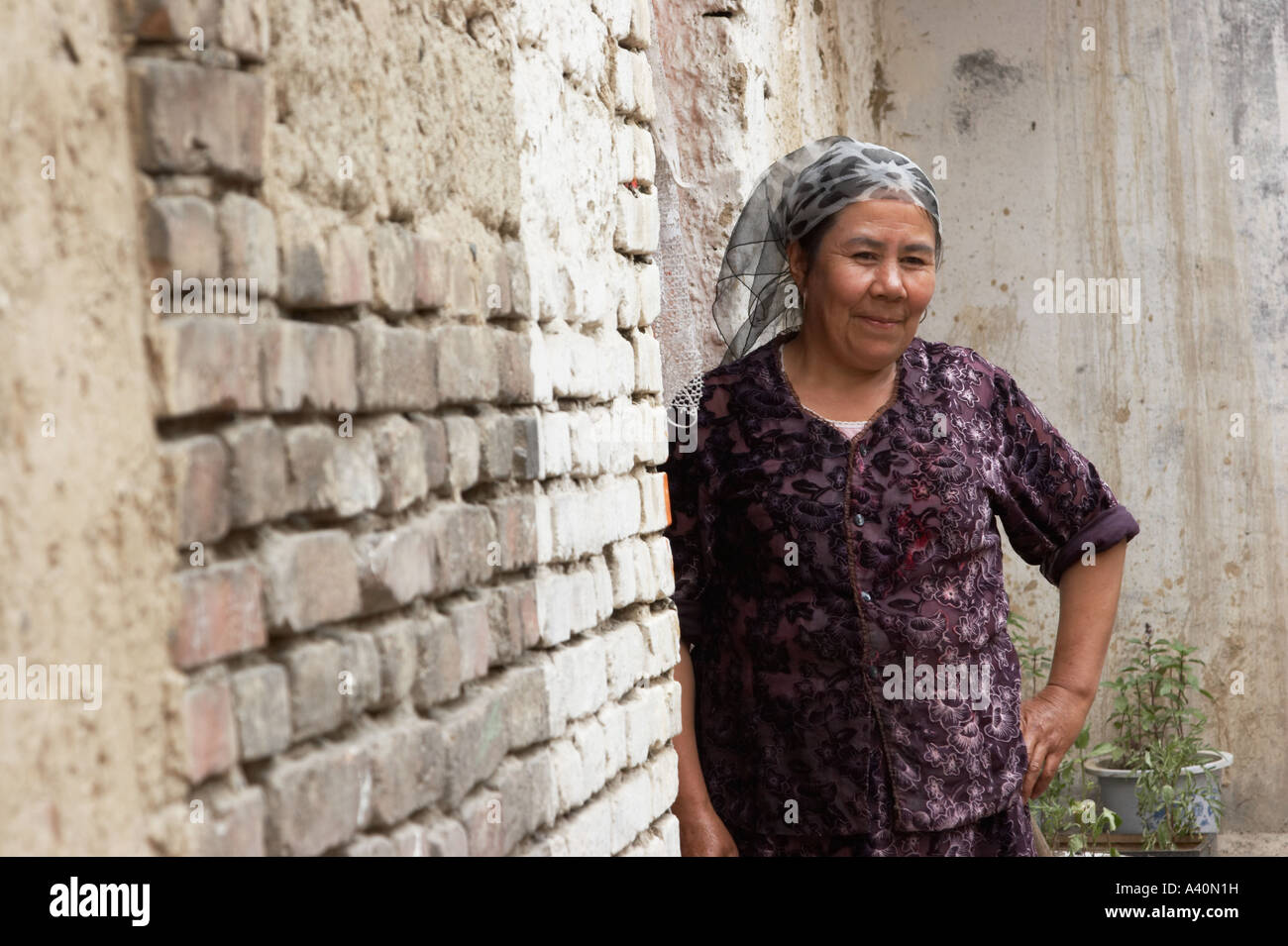 Anziani Uighur donna in piedi fuori casa Foto Stock