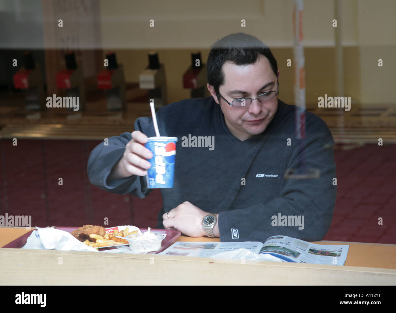 Uomo in cafe di mangiare cibo spazzatura Foto Stock