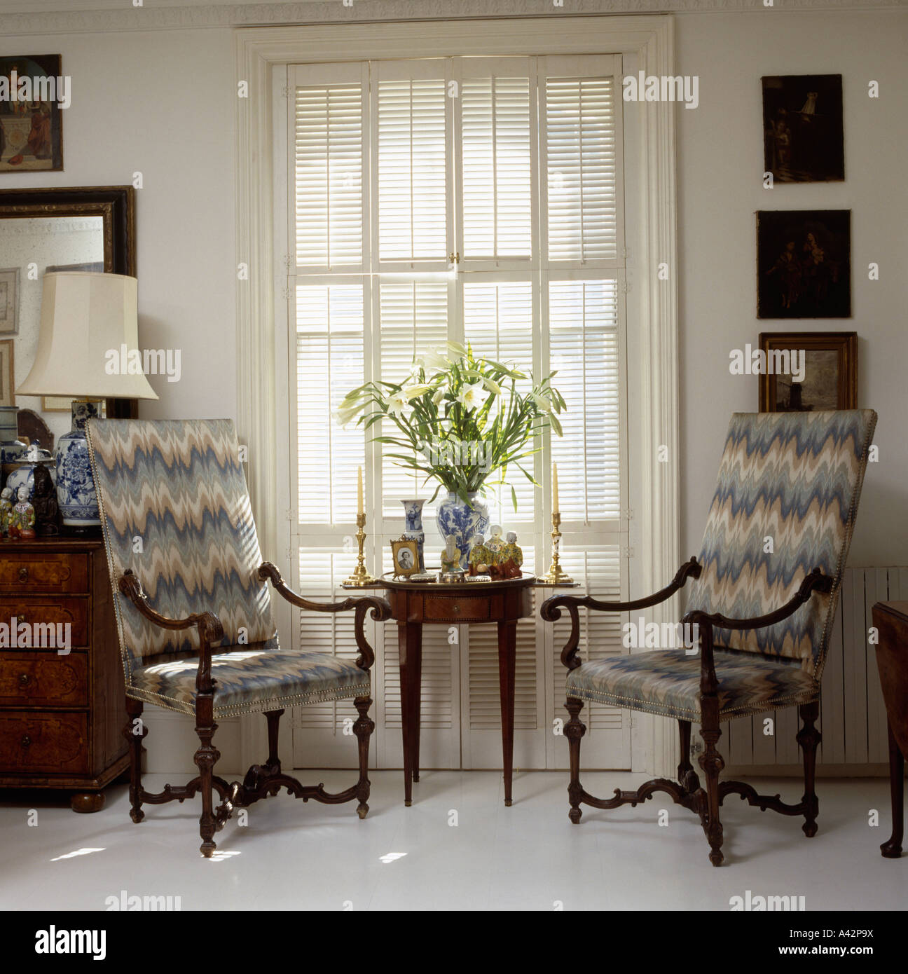 Le poltrone con blu arazzo fiorentino imbottitura nella parte anteriore della finestra con la piantagione di persiane louvre Foto Stock
