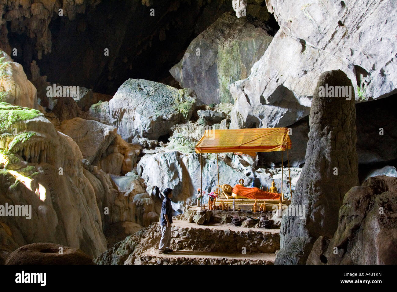 Turista nella parte anteriore del reclinabili Buddha in bronzo all'interno di Phu Kham Grotta Vang Vieng Laos Foto Stock