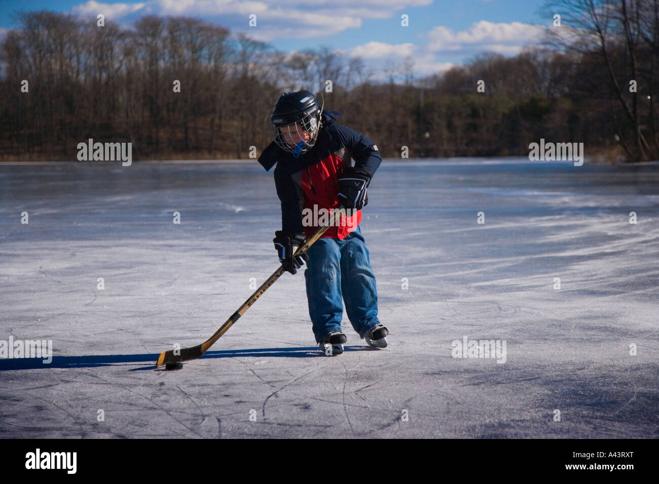 Ragazzo giocare hockey su ghiaccio su un laghetto congelato Foto Stock