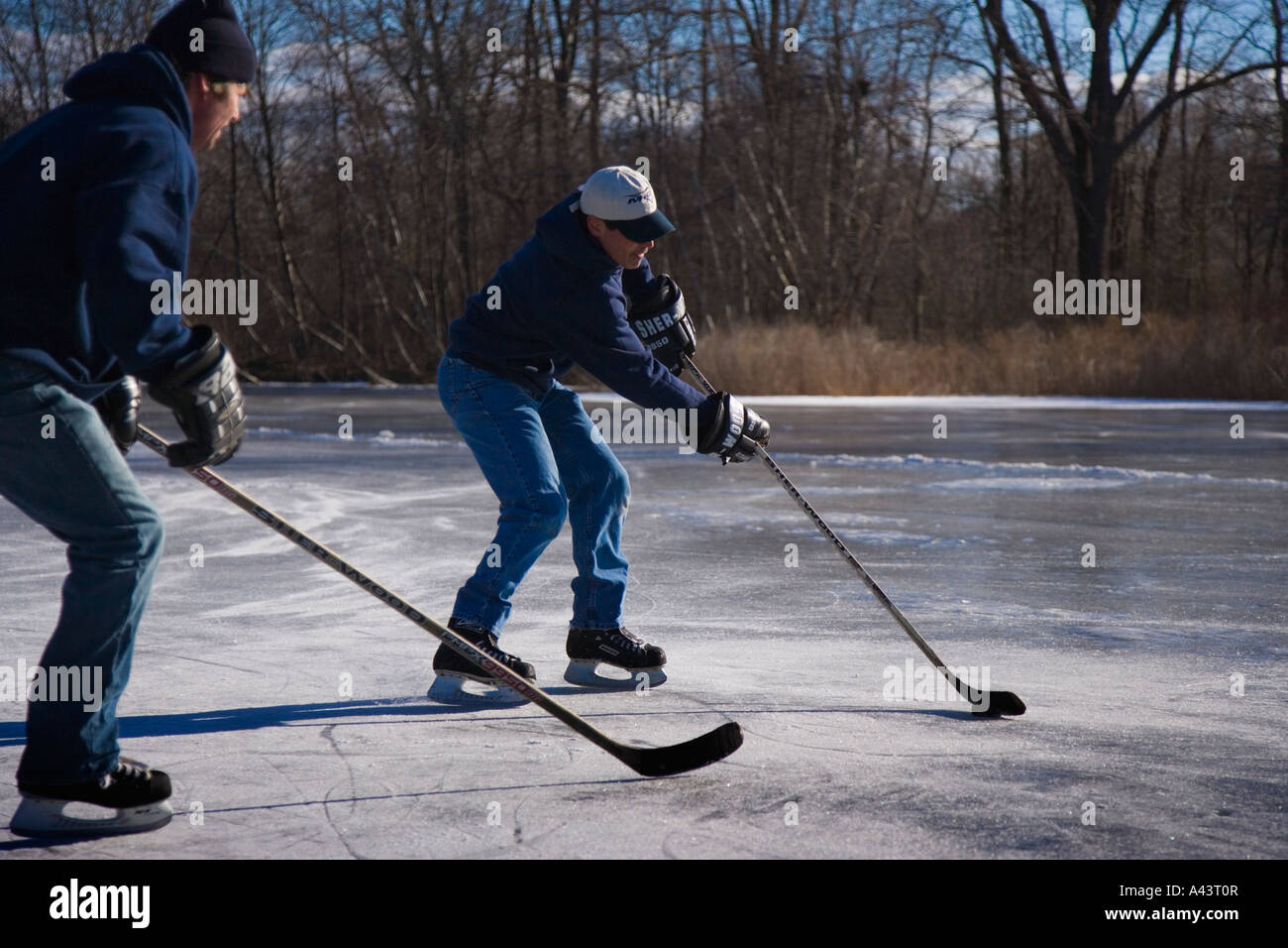 Due uomini giocare hockey su ghiaccio su un laghetto congelato Foto Stock