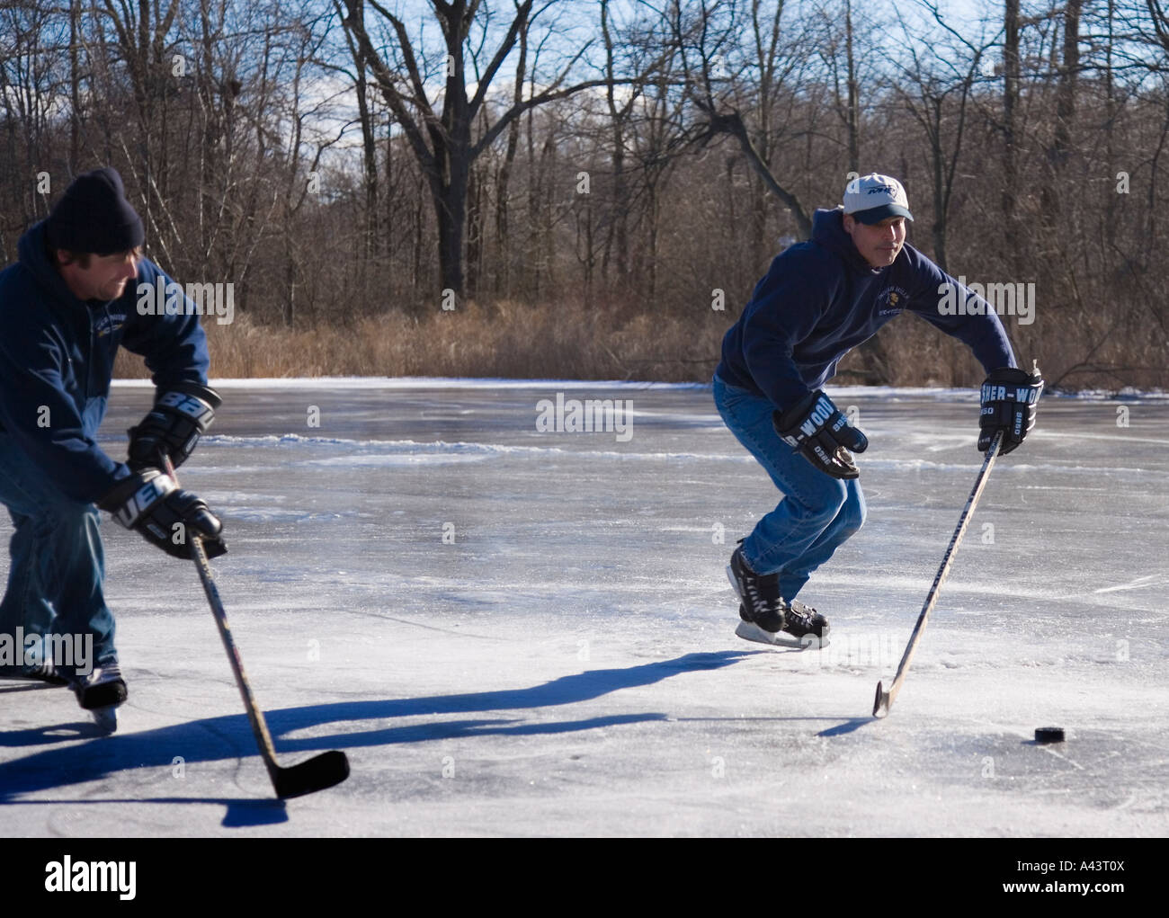 Due uomini giocare hockey su ghiaccio su un laghetto congelato Foto Stock