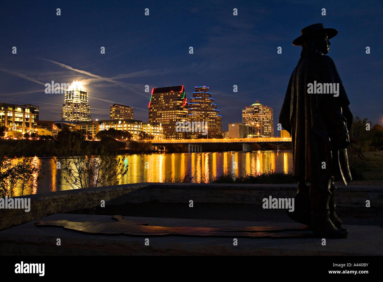 Austin Texas Stevie Ray Vaughan Memorial statua lungo il Town Lake skyline della città notte Congress Street bridge Fiume Colorado Foto Stock