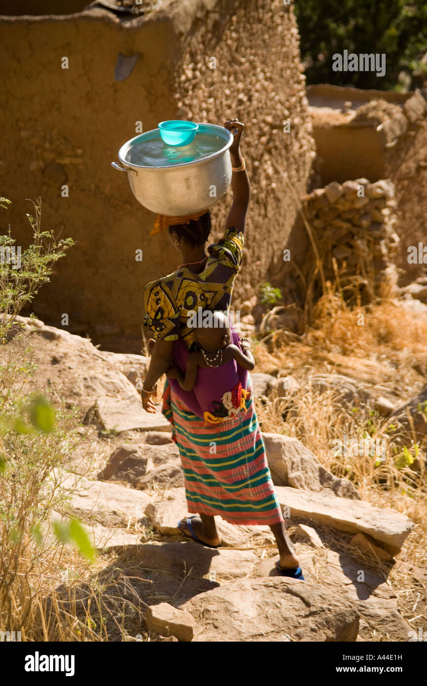 Donna africana per la raccolta delle acque nel villaggio di banani e la scarpata, Paese Dogon del Mali, Africa occidentale Foto Stock