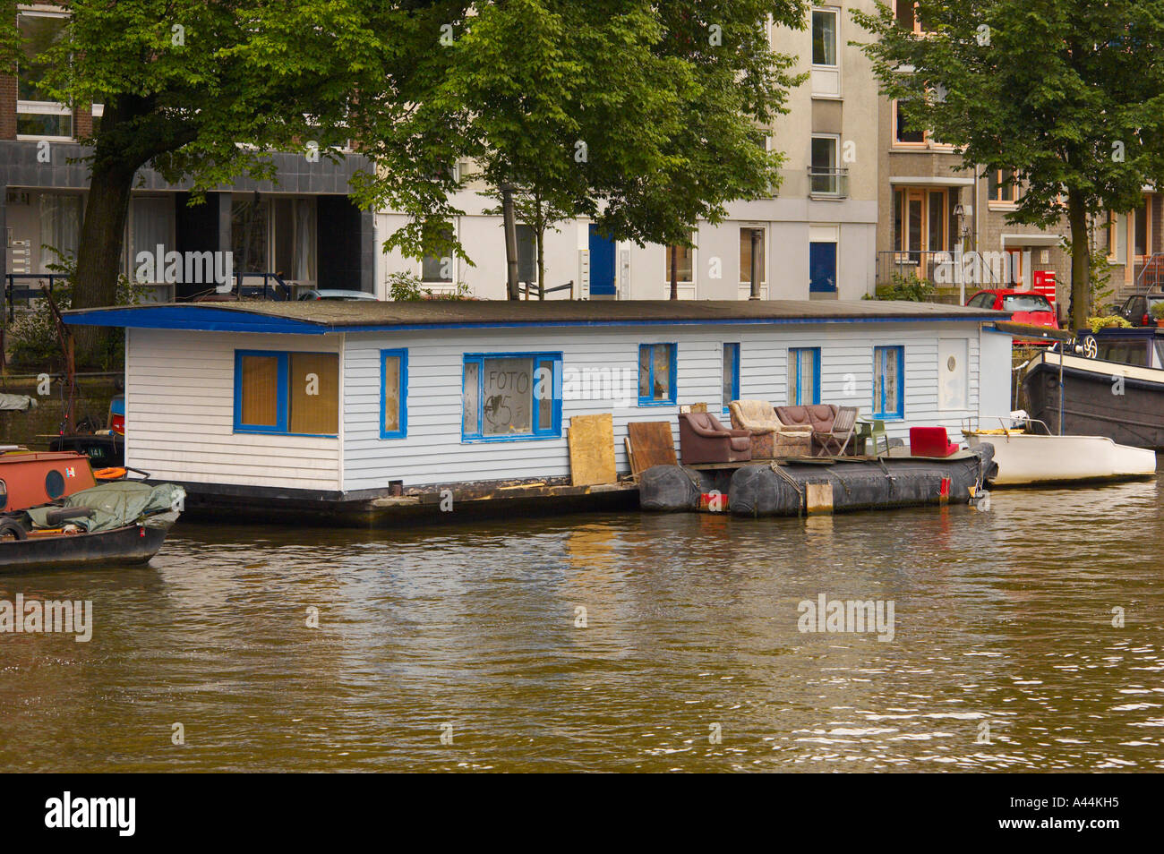 Casa galleggiante ormeggiata con posti a sedere all'aperto sul fiume Amstel ad Amsterdam. Paesi Bassi Foto Stock