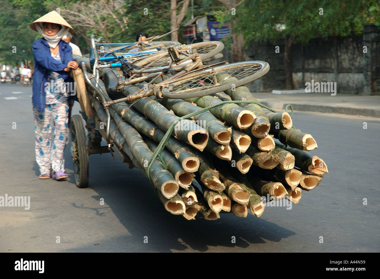 Poli di bambù spinto sul carrello con ruote da una donna in strada di Hoi An Vietnam Viet Nam Asia Foto Stock