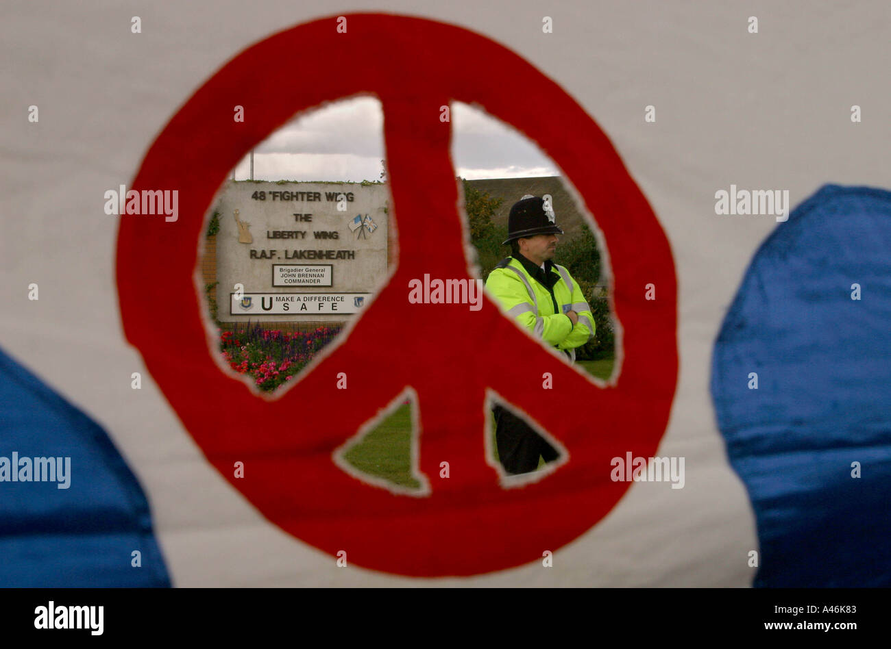 Dimostrazione di pace a lakenheath airbase un poliziotto all'ingresso lakenheath airbase è visto attraverso una campagna per il disarmo nucleare banner in una veglia e la dimostrazione al di fuori della base aerea nel Suffolk, Inghilterra 7 ottobre 2002 l'Airbase è la casa degli Stati Uniti airforce 48th Fighter Wing utilizzando f1 11 fighter bombardieri che sarà distribuito in qualsiasi futura azione militare contro l'iraq la base inoltre memorizza un numero di esclusive delle armi nucleari Foto Stock