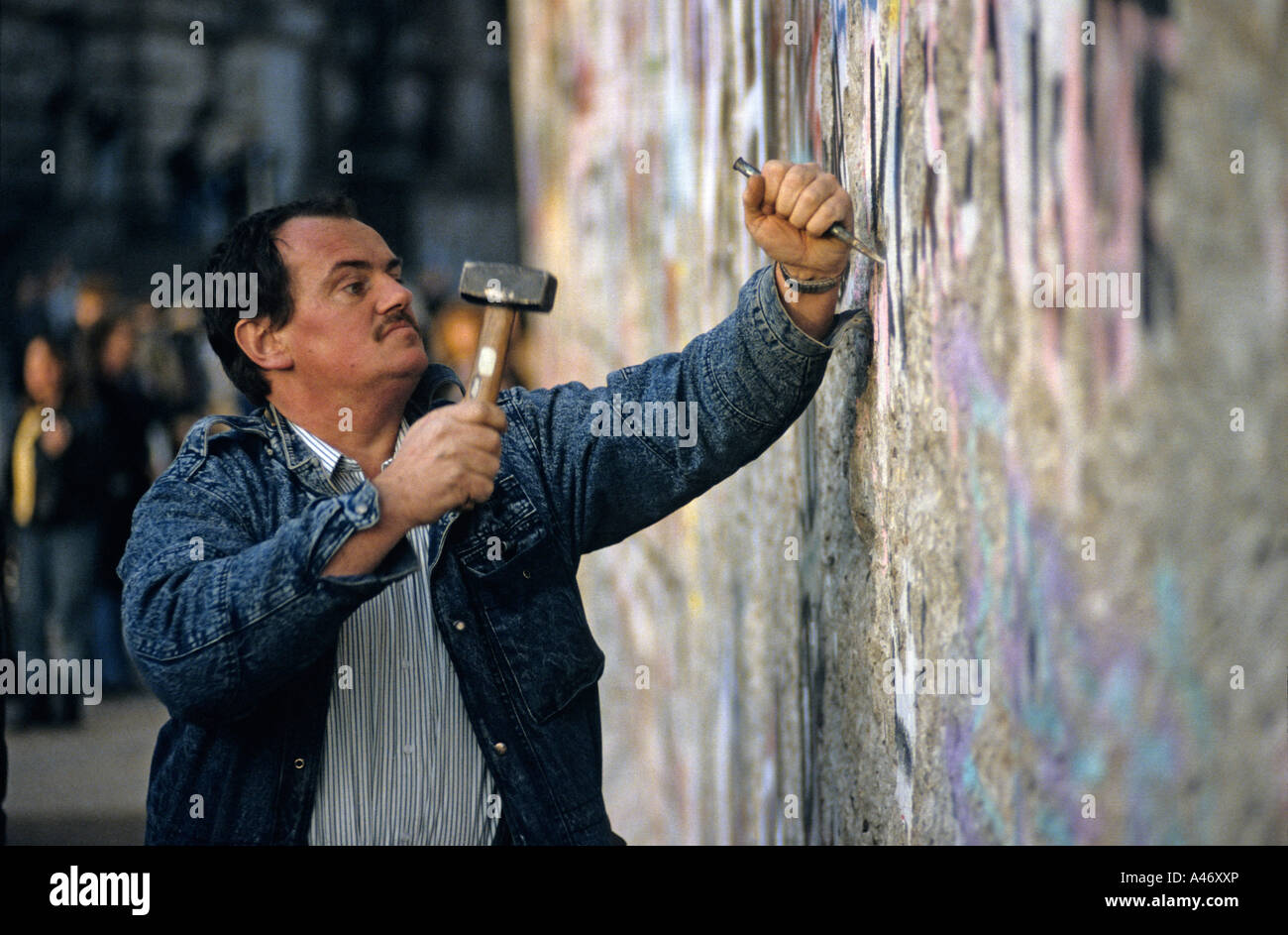 Caduta del muro di Berlino: uomo scalpellatura pezzi fuori dalla parete (Mauerspecht), Berlino, Germania Foto Stock