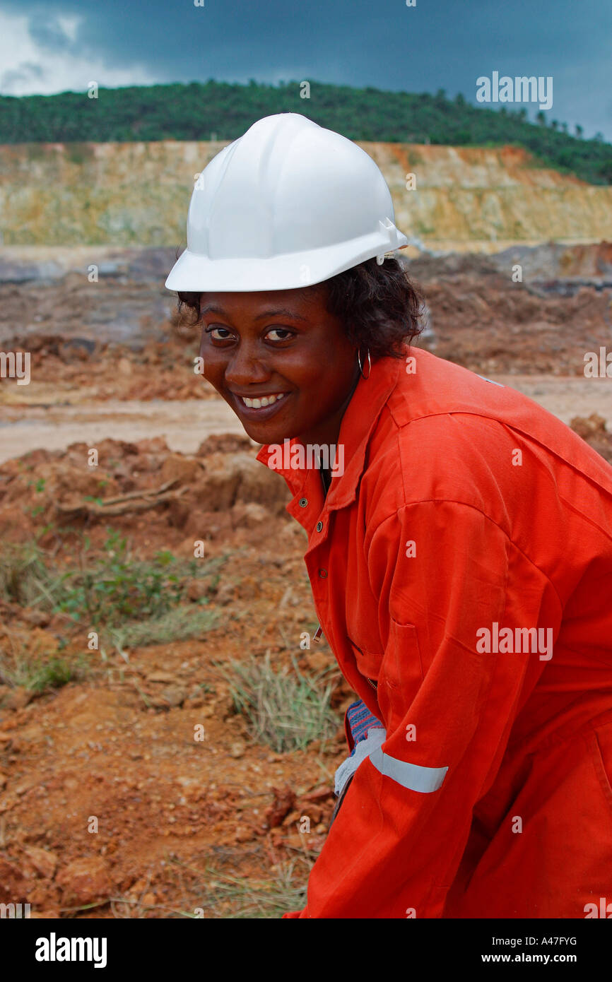 Riabilitazione assistente di campo piantando erba sul bordo della superficie a cielo aperto miniera d'oro pit, Ghana, Africa occidentale Foto Stock