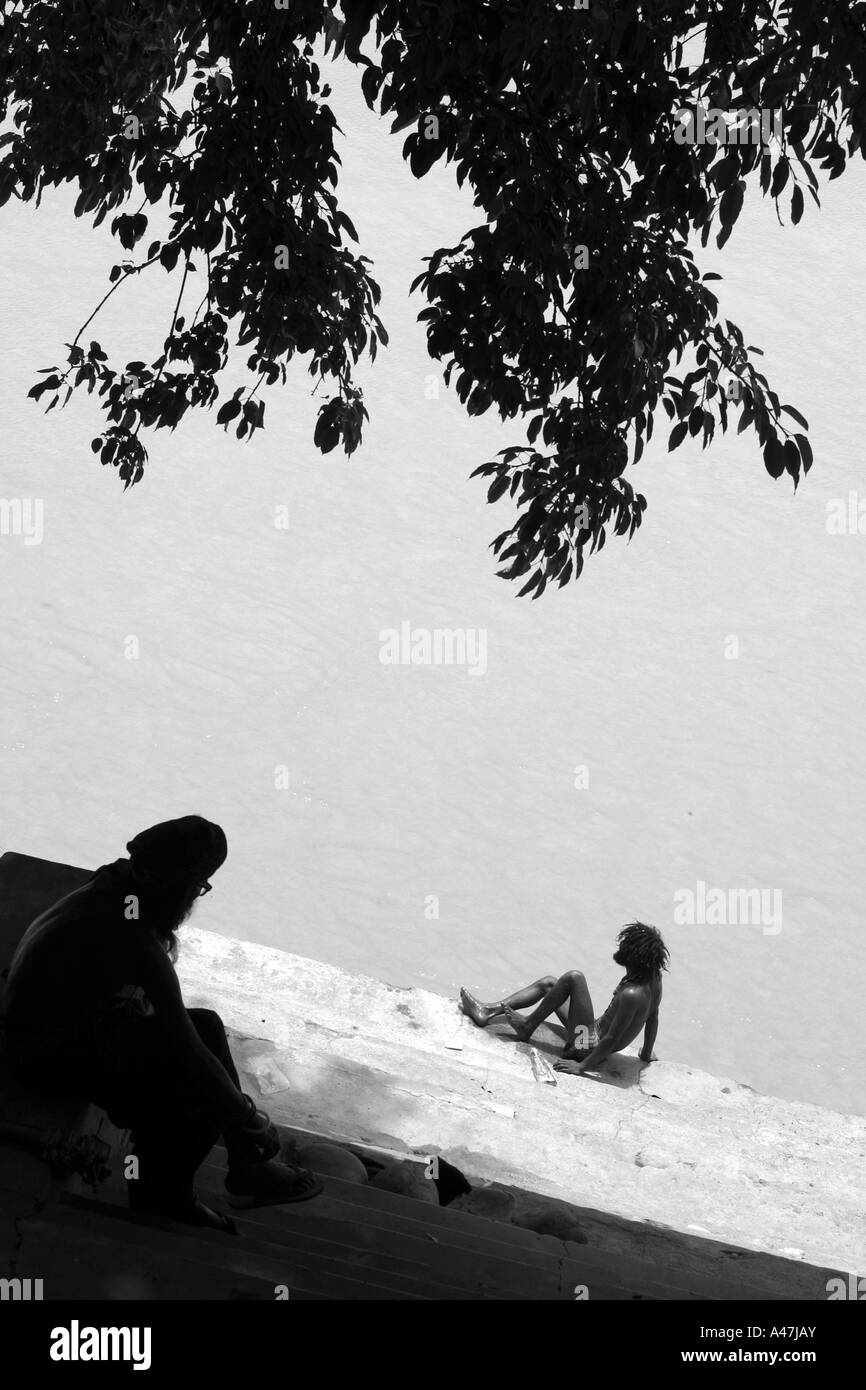 Un uomo indù si siede presso la banca di fiume santo del Gange a Rishikesh in India Foto Stock