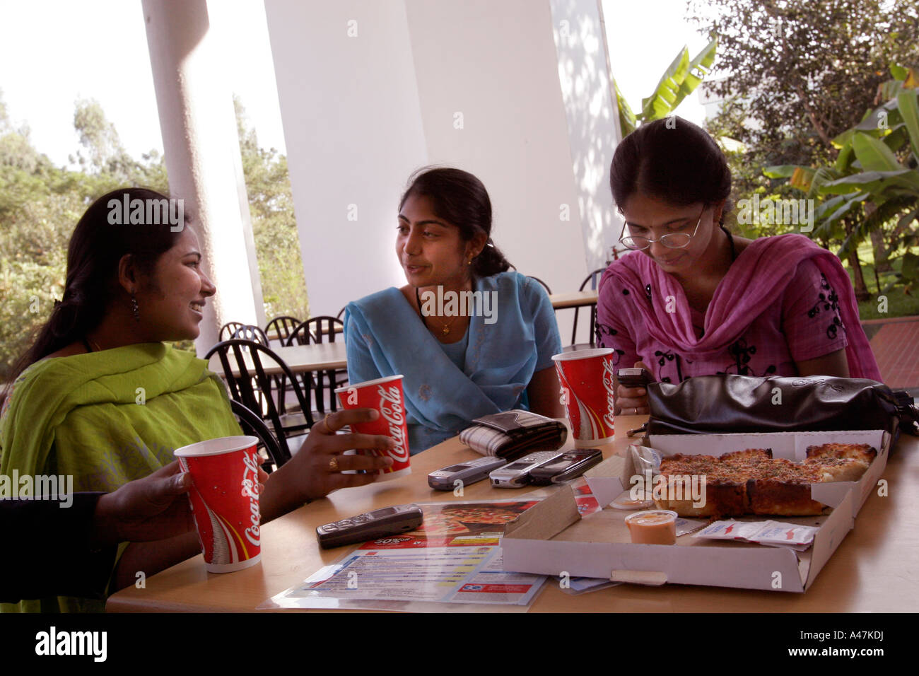 Giovani donne indiane che lavora nel settore IT per Infosys mangia fast food occidentali durante una pausa pranzo a Bangalore in India Foto Stock