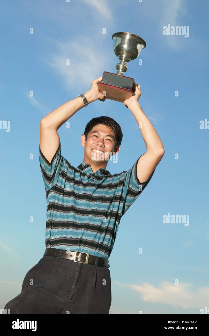 Uomo asiatico tenendo un trofeo Foto Stock