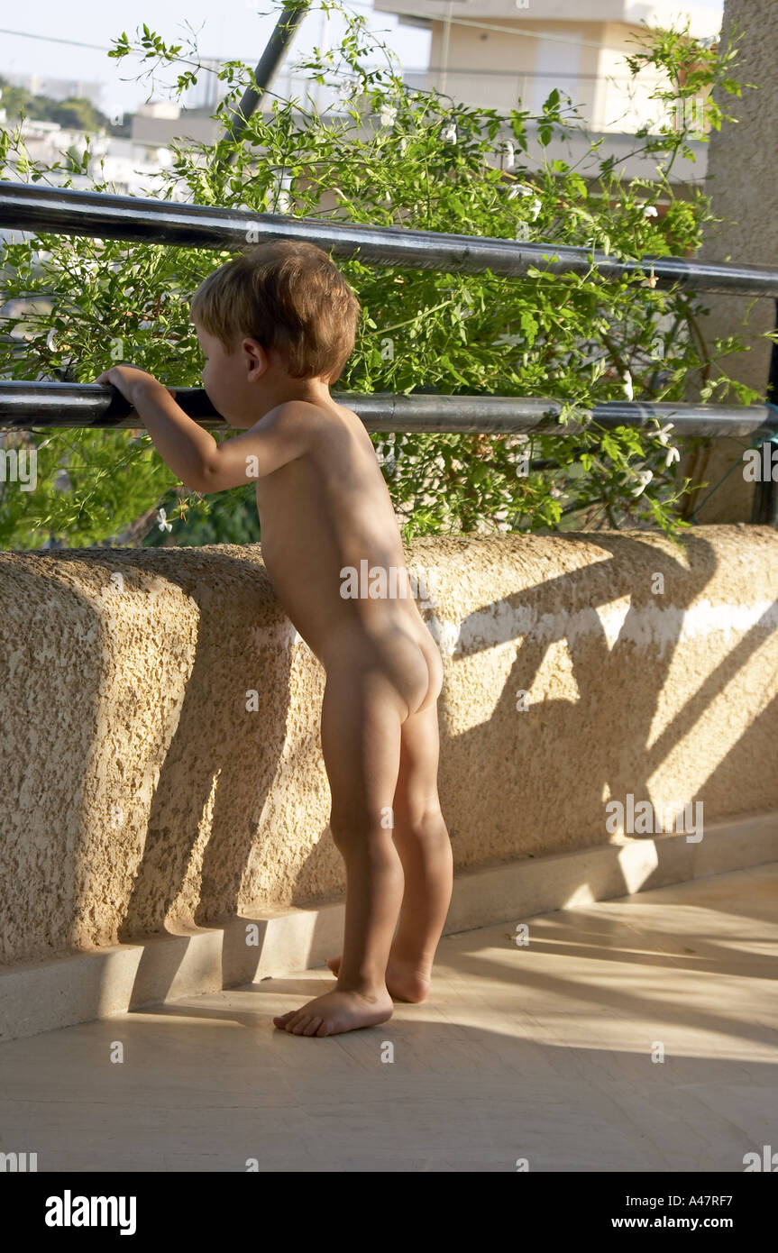Ragazzo giovane nudo nudi nudi o in piedi su un balcone Foto Stock