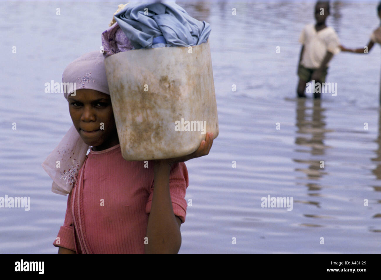 La donna che porta i suoi possedimenti attraverso acqua dopo il fiume Nilo inondati di Khatoum Foto Stock