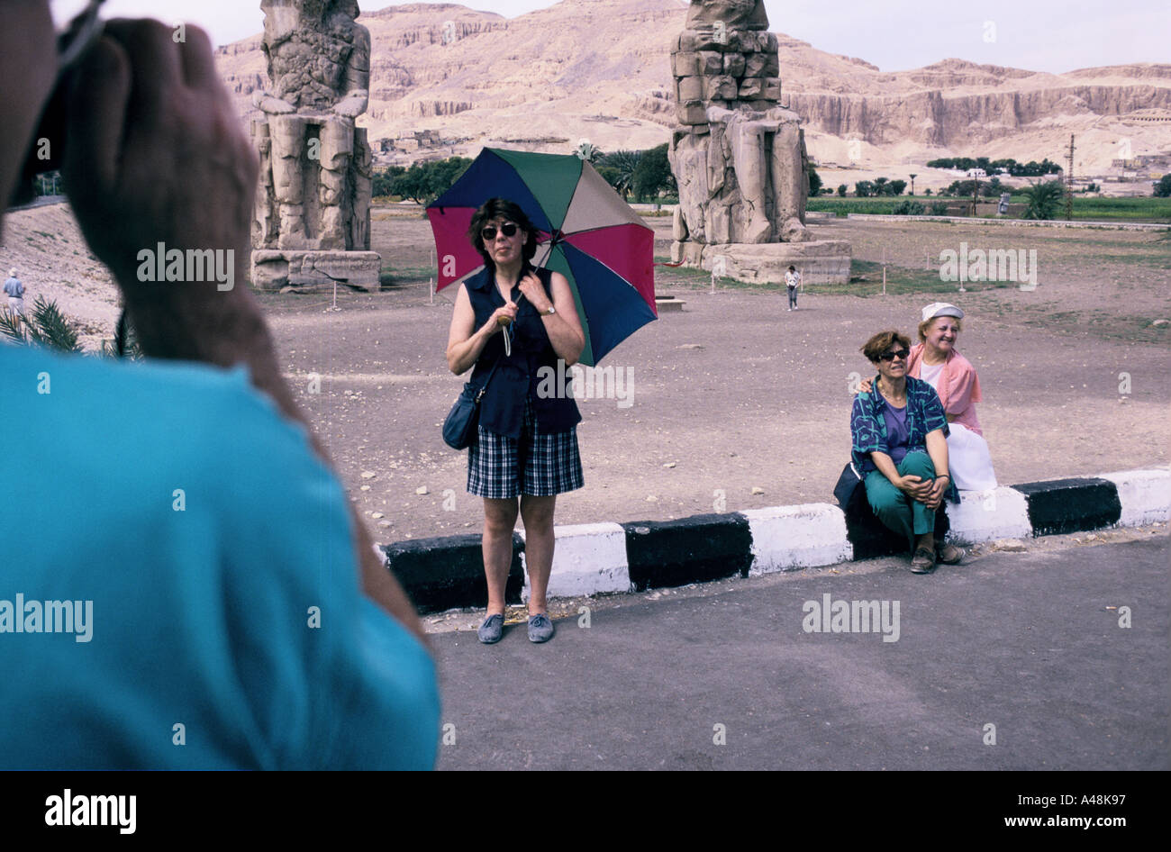 I turisti provenienti da una nave da crociera che posano per una foto di i Colossi di Memnon nella valle dei re in Egitto Foto Stock