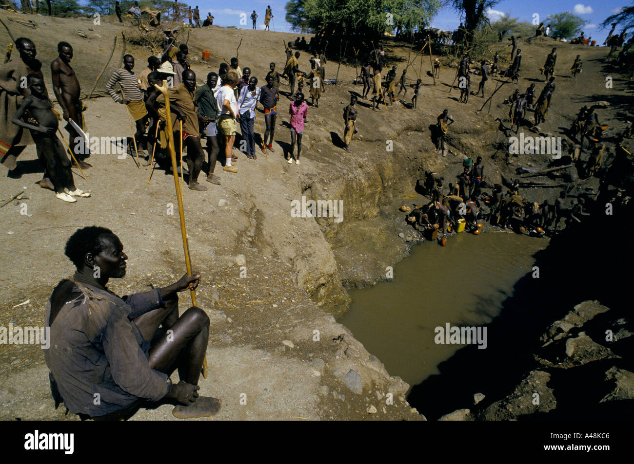 Fame spostato Dinka e Tuposa persone intorno a un waterhole in Naruse Sudan meridionale 1986 Foto Stock