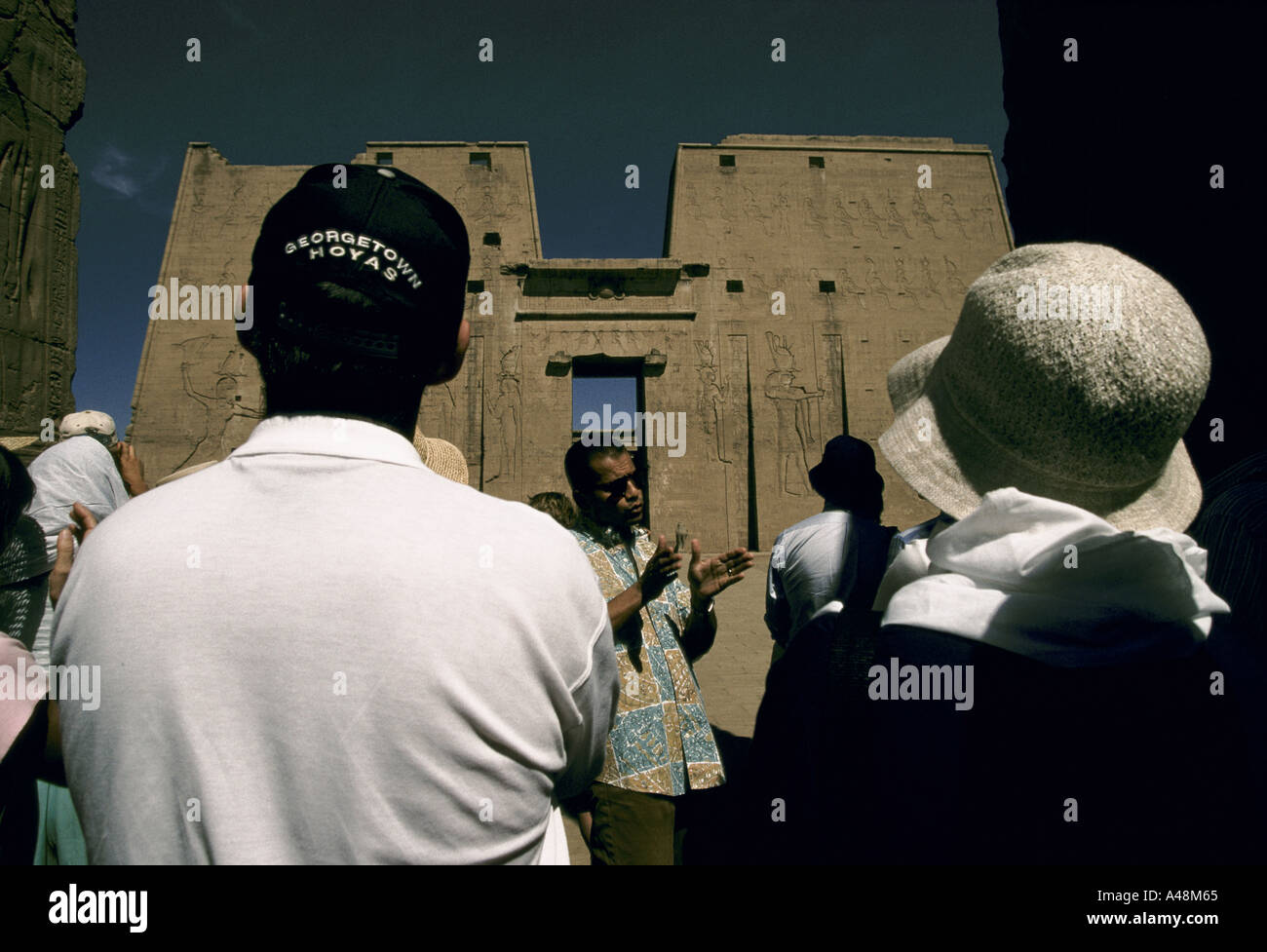 Un gruppo di turisti ascoltando una guida turistica visitando il Tempio di Horus in Etfu nella valle del Nilo , Egitto Foto Stock