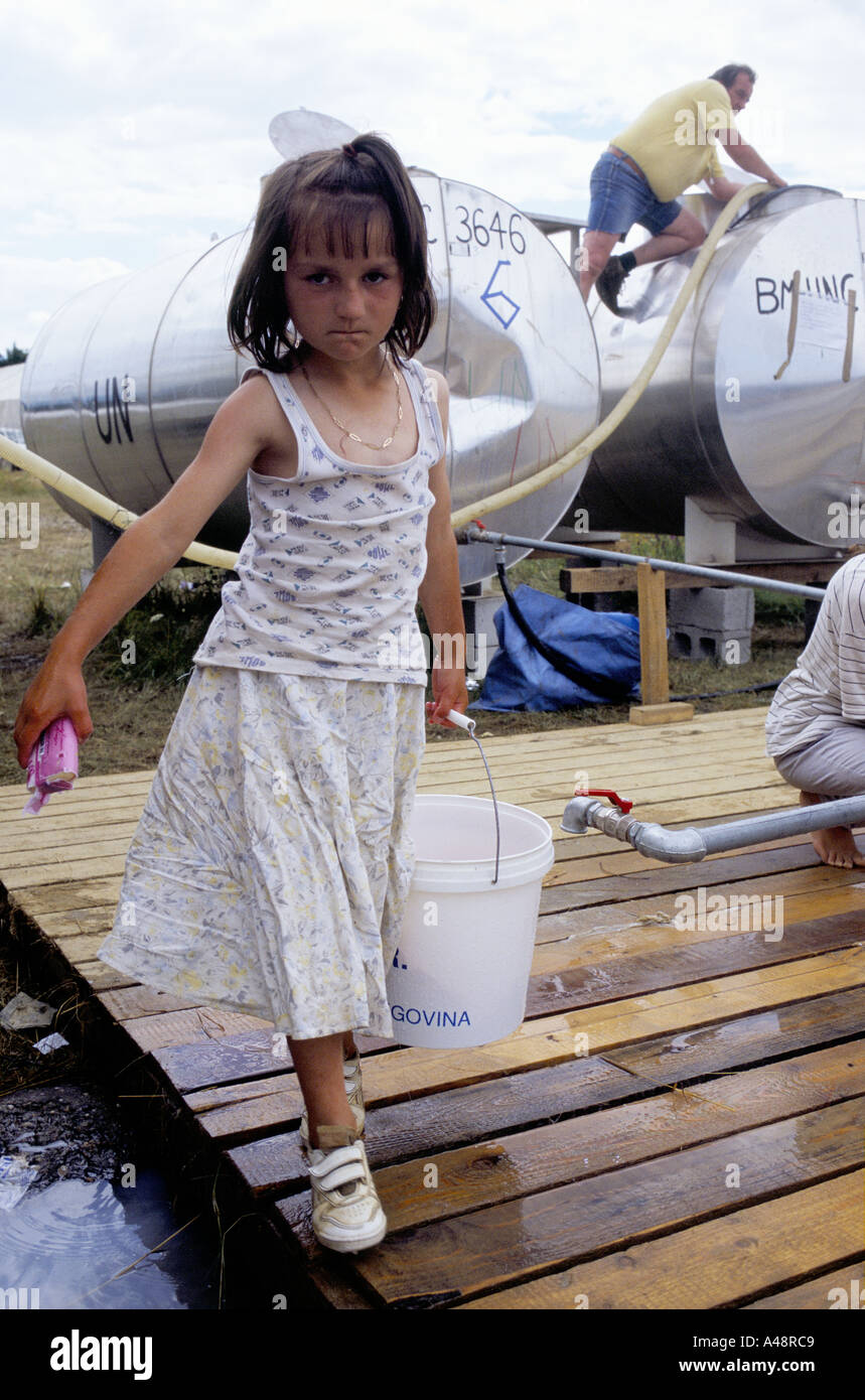 Refugee ragazza di Srebrenica la raccolta di acqua da un tubo montante luglio 1995 .aerodromo Tuzla Refugee Camp Foto Stock