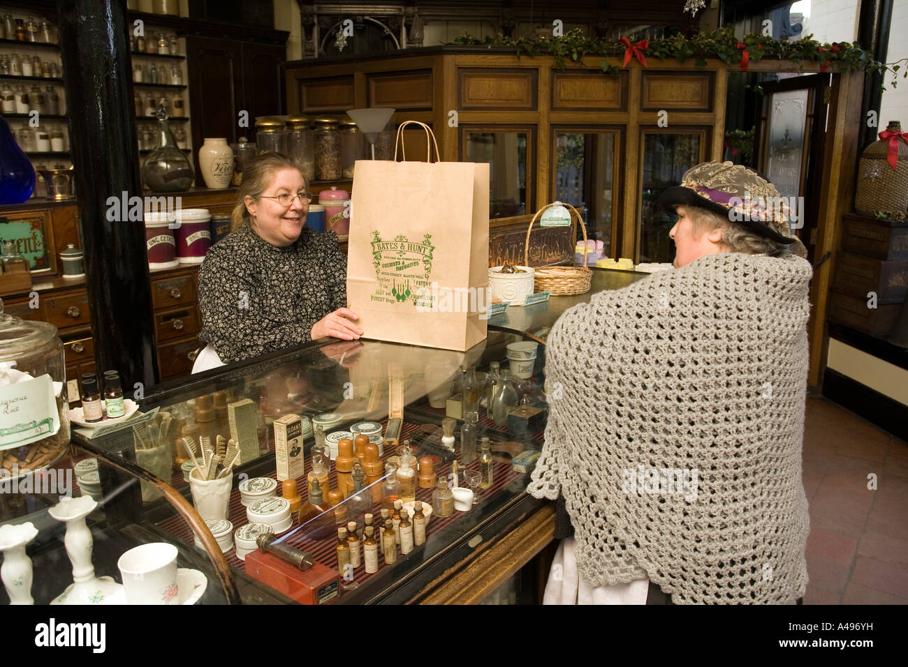 Regno Unito Shropshire Ironbridge Blists Hill Victorian farmacia comunale che serve clienti in costume a Natale Foto Stock