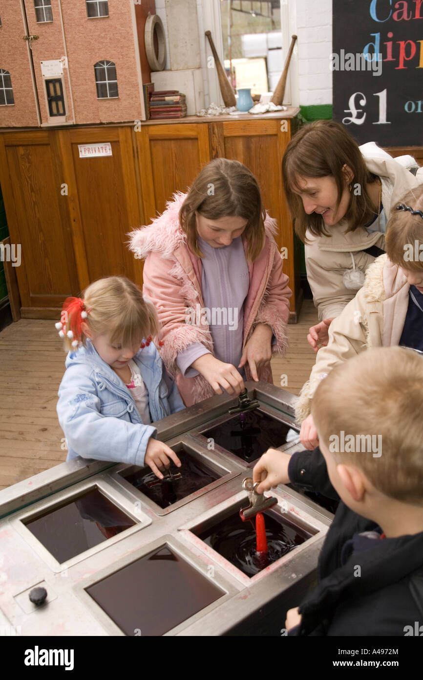 Regno Unito Shropshire Ironbridge Blists Hill Museum a Natale i bambini fare candele mediante immersione in cera calda Foto Stock