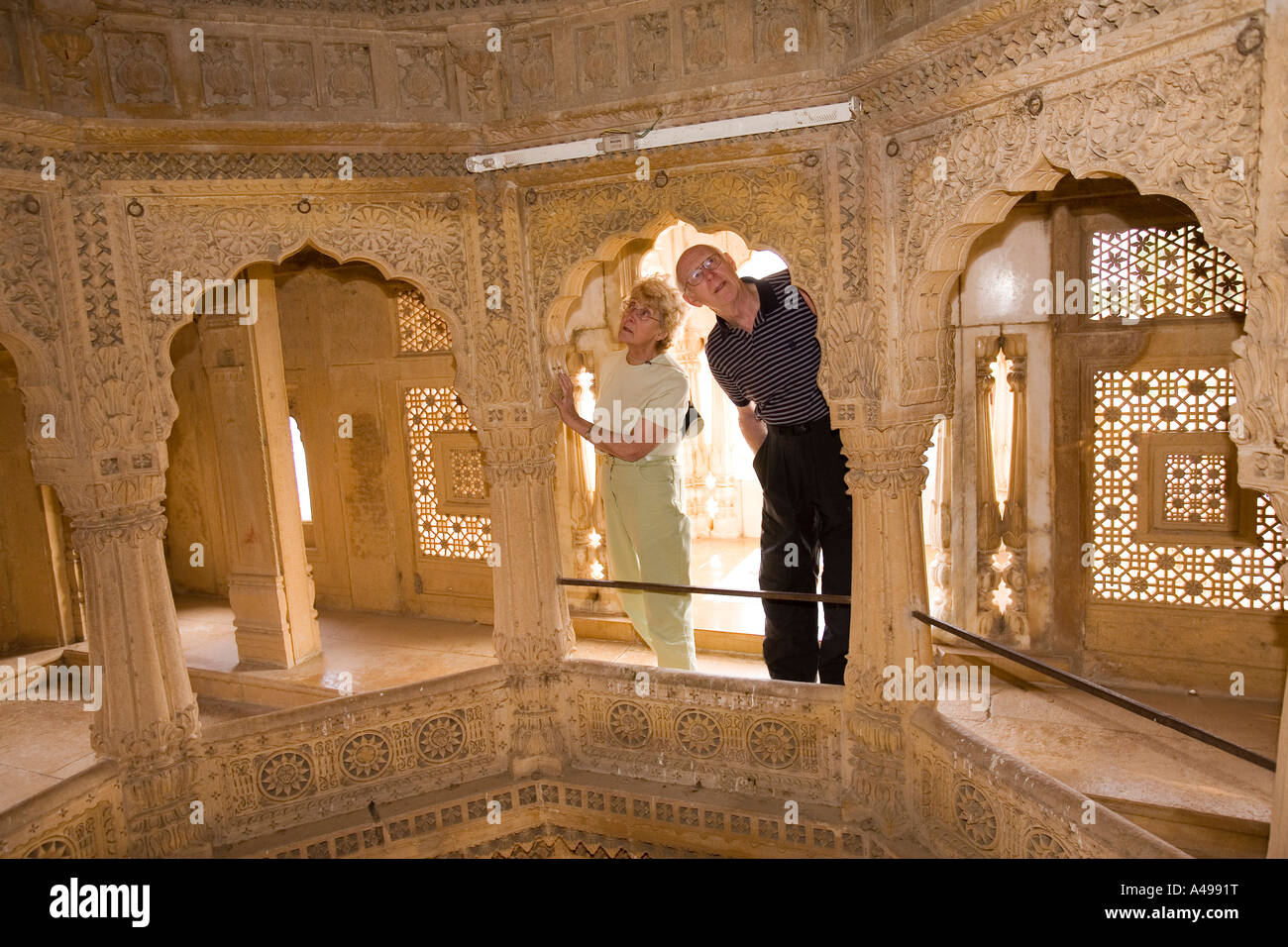 India Rajasthan Jaisalmer Amar Sagar del XIX secolo in pietra arenaria scolpita tempio Jain i turisti occidentali guardando interno Foto Stock