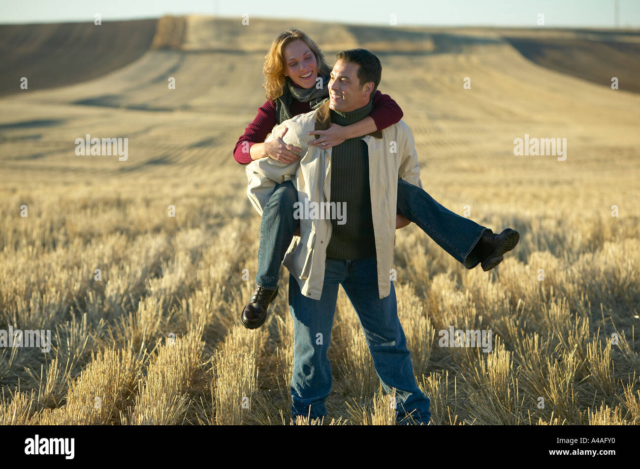 Donna che ride su mans indietro nel taglio di erba Campi in autunno Colorado Foto Stock