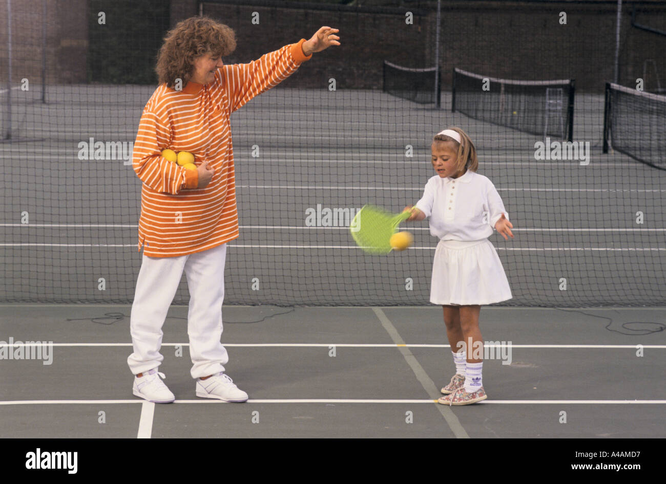 Una giovane ragazza che impara a giocare a tennis con una racchetta in plastica con private coaching, Londra, Regno Unito. Foto Stock