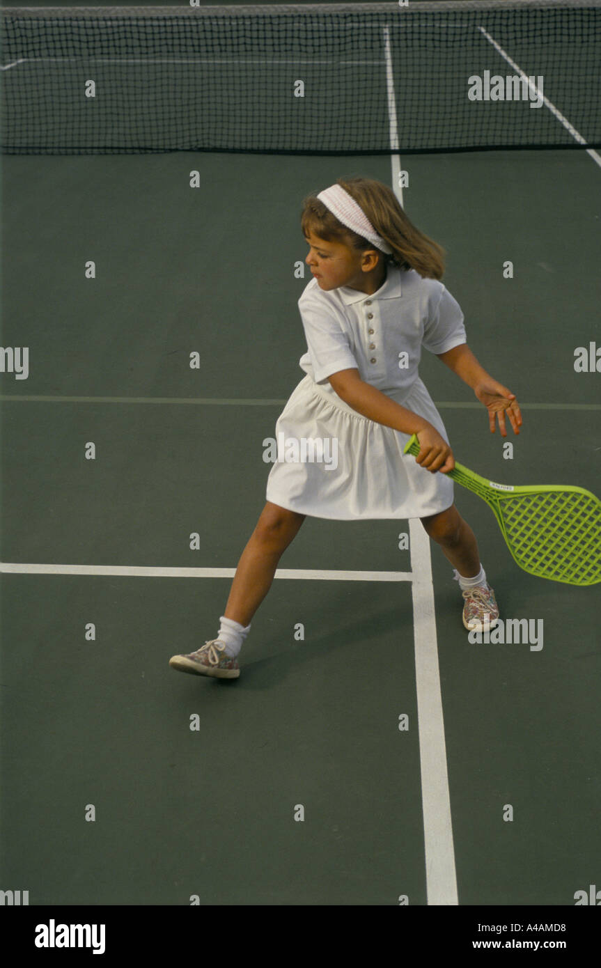 Una giovane ragazza che impara a giocare a tennis con una racchetta in plastica con private coaching, Londra, Regno Unito. Foto Stock