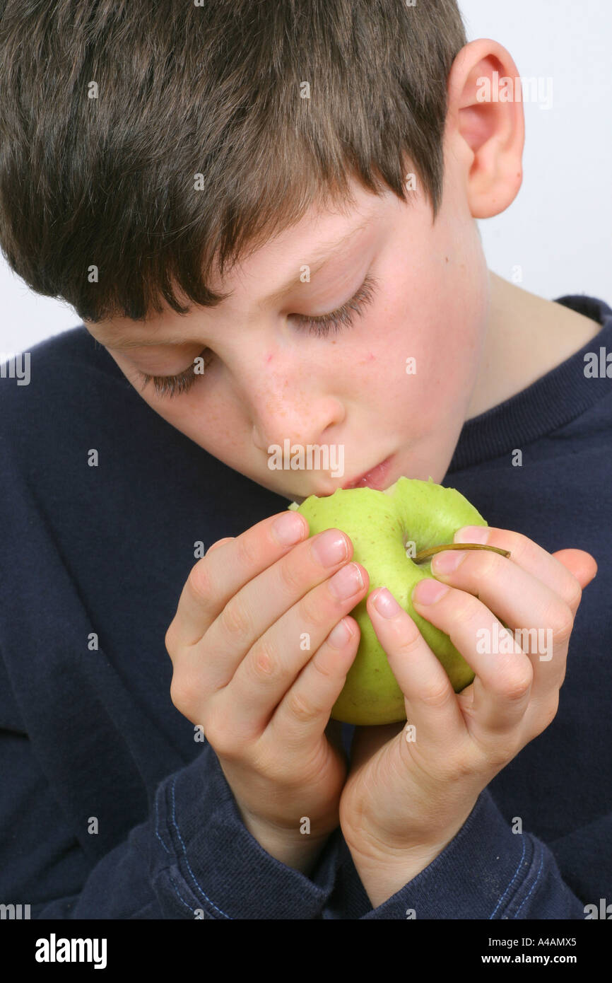 Un bambino di otto anni di mangiare una mela golden delicious a casa. Foto Stock
