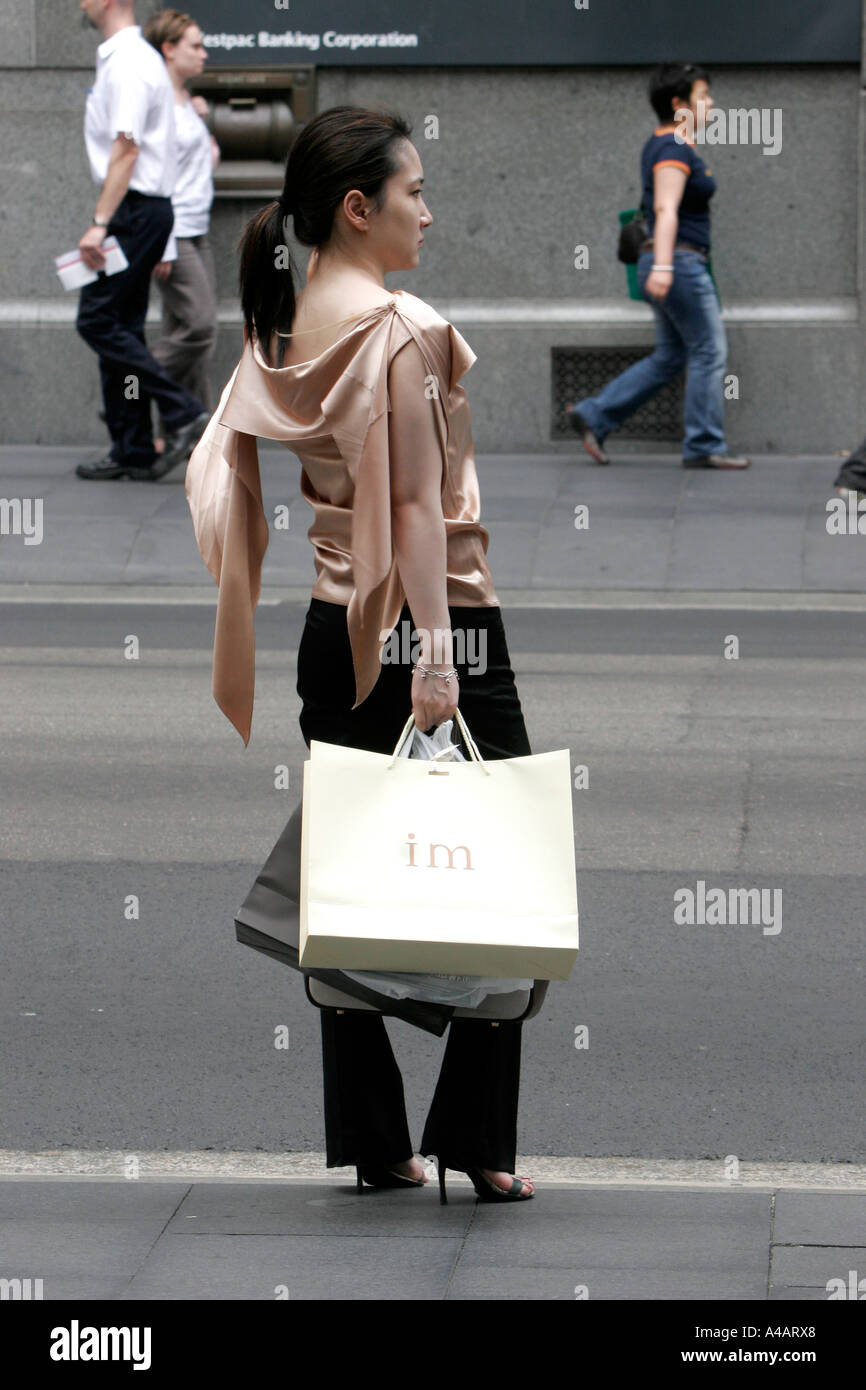 Un elegante e sottile donna asiatica saluta un taxi dopo lo shopping Foto Stock Un elegante e sottile donna asiatica saluta un taxi dopo lo shopping Foto Stock