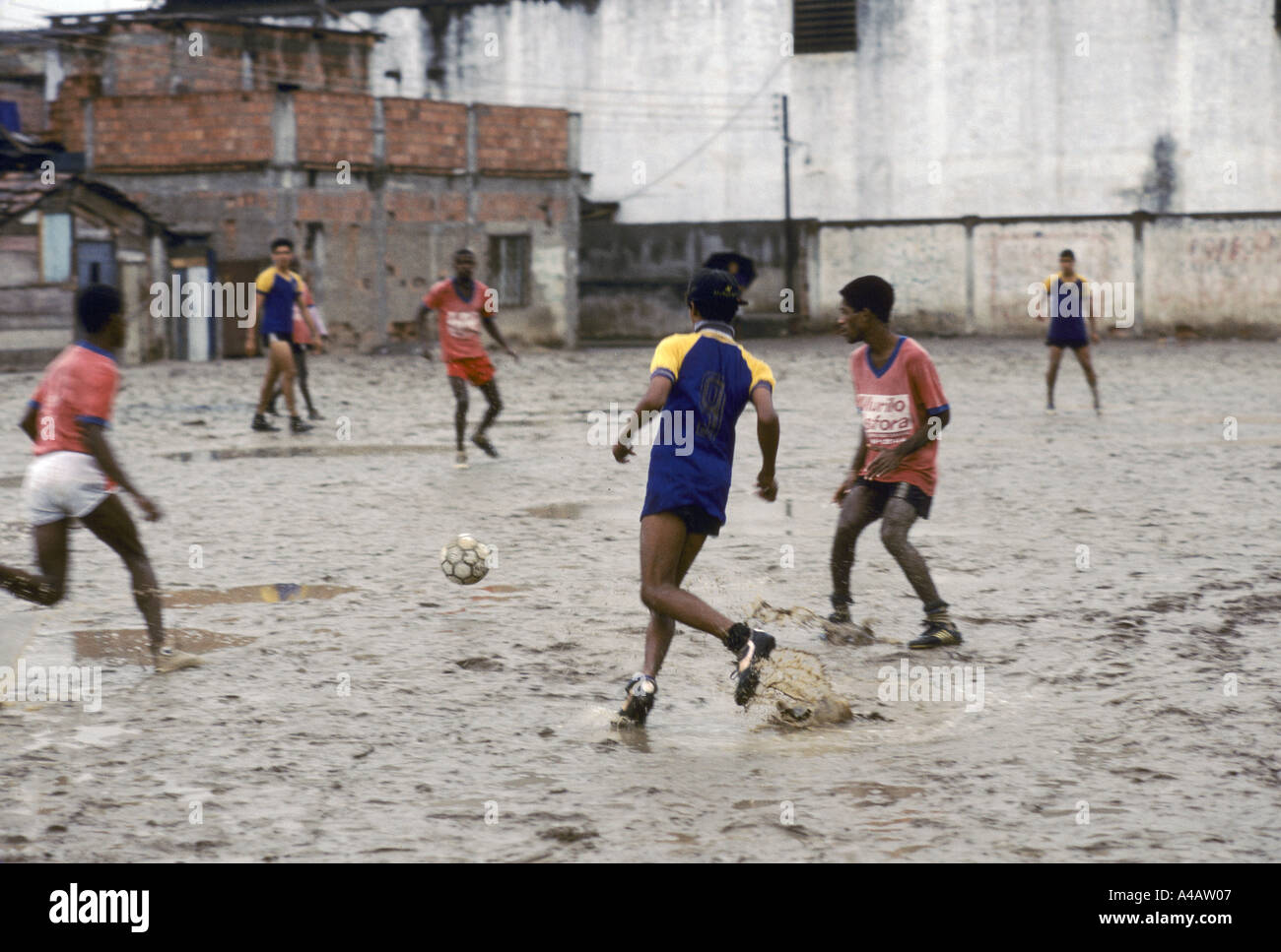 Bambini che giocano a calcio in un terreno fangoso, MARE FAVELA, RIO BRASILE. Foto Stock
